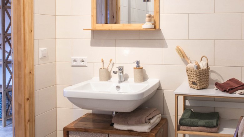 Bathroom detail, © Monika Pölzer Modern bathroom with wooden details, washbasin, mirror and shelves.