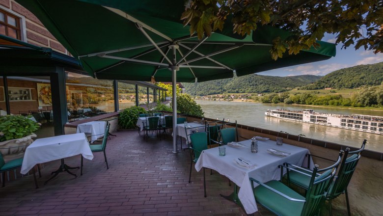 Hotel Schloss Dürnstein, © Niederösterreich Werbung / Maximilian Pawlikowsky Terrace of Hotel Schloss Dürnstein with a view of the Danube and a passing ship.
