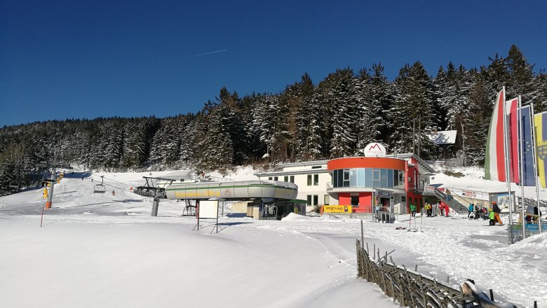 Start chair lift Mönichkirchen, © Józef Swierkot Chairlift station in Mönichkirchen in winter with snow-covered terrain and forest in the background.