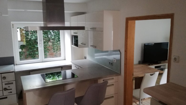 Kitchen, © Günter Lammer Modern kitchen with cooking island, white cupboards and window with a view of the greenery.