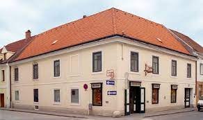Bakery Kustor, © Bäckerei Kustor Corner building with red tiled roof and several signs, including one with the inscription 'Bäckerei' (bakery).