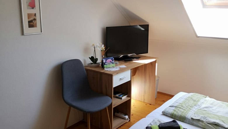 Room 2, © Haselberger A cozy room with a bed, a small desk with TV, a chair and a skylight.