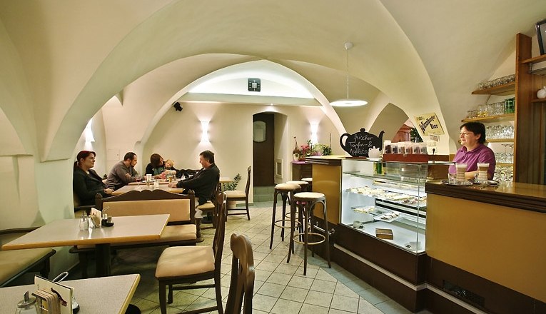 Café Colibri, © Susanne Karas Interior view of a cozy café with a vaulted ceiling, tables and a bar.