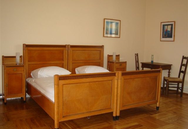 Jakob - Kern Guest House, Geras Abbey***, © Jakob-Kern Gästehaus A traditionally furnished guest room with two single beds made of wood, a table, chairs and pictures on the wall.