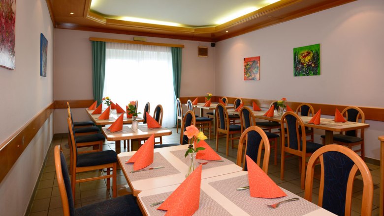Dining room Gasthof Schmied Smolka, © Gasthof Schmied Smolka A dining room with laid tables, orange napkins and vases of flowers.