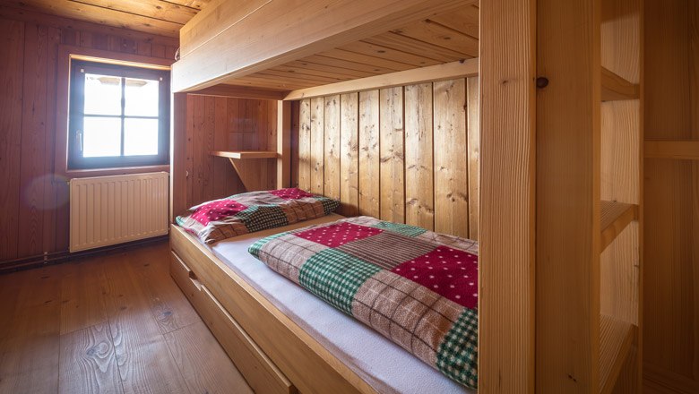 Spend the night on the Hochwechsel, © Wiener Alpen, Christian Kremsl Wood-paneled room with bunk beds and checkered ceilings.