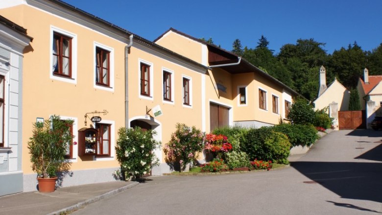 House, © Familie Arocker Yellow house with flowers and blue sky in the background.