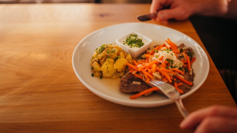 Boiled beef, © Niederösterreich Werbung/Daniela Führer Plate with meat, carrots, potatoes and dip on wooden table.