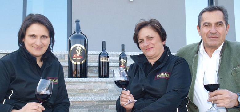 Ipsmiller family, © Weingut Ipsmiller Three people sit on steps with wine glasses and bottles of wine.