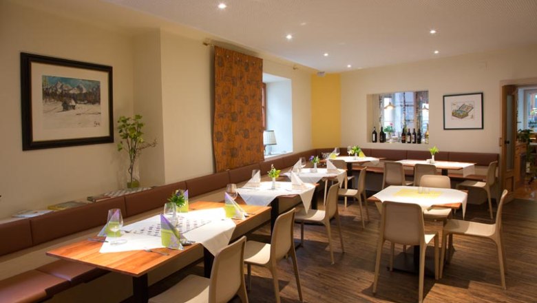 Dining room, © Gerhard Böhm A modern dining room with laid tables, chairs and decorations. Pictures hang on the walls and there is a windowsill with bottles of wine.
