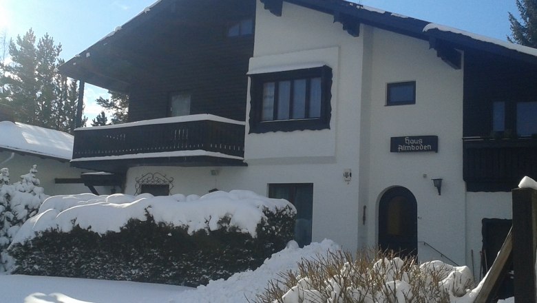 House Almboden, © Fam. Ullram A snow-covered house with wooden balcony and 'Haus Almboden' sign.