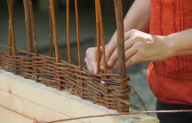 Historical craftsmanship, © MAMUZ Person weaves willow branches into a basket.