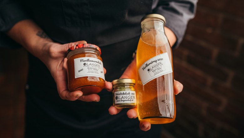 Jams, syrups and chutneys from Langer, © Niederösterreich Werbung/Daniela Führer Person holding jars of apricot jam and elderberry syrup from Langer.