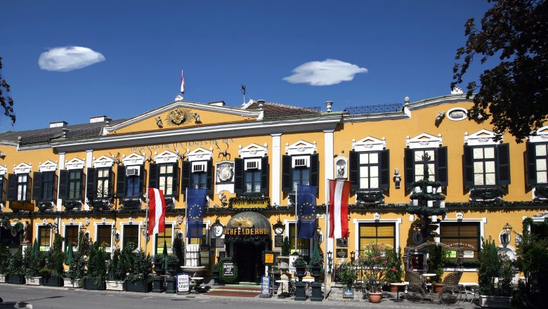 Marchfelderhof, © Gault Millau Yellow building with black shutters and Austrian flag.