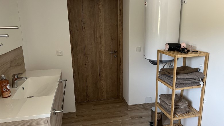 Bathroom, © Anton Sommer Modern bathroom with wooden shelves, towels, washbasin and hot water boiler.
