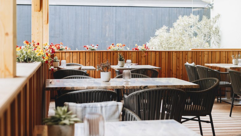 Tranquil garden in the inner courtyard, © Niederösterreich Werbung/David Schreiber A cozy courtyard with wooden furniture and flower arrangements on the tables.