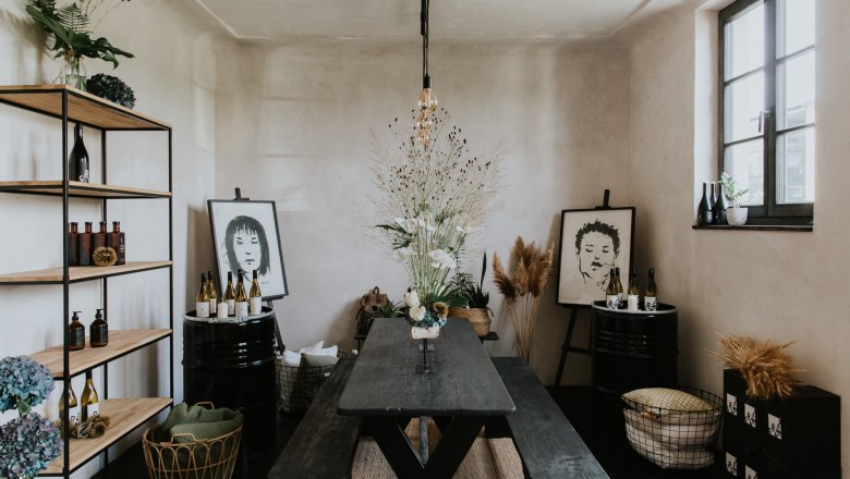 Franz von Grün, © Agentur Werbereich, Bianca Hochenauer A stylishly furnished room with a wooden table, shelves, plants and works of art on the walls.