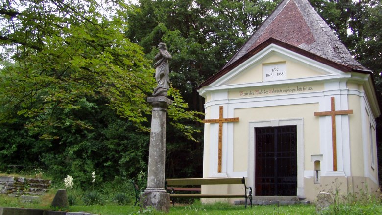 Weitersfeld, © Weitersfeld Chapel with statue and cross in a green park.