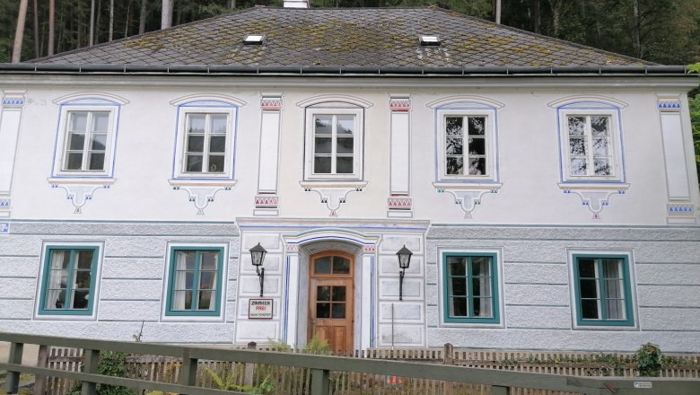 House view, © Wiener Alpen Historic building with ornate windows and wooden door, surrounded by forest.