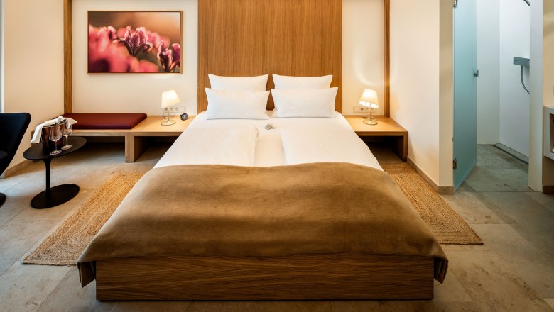 Guesthouse Flora, © Herbert Lehmann Modernly furnished hotel room with double bed, bedside tables, lamps and a picture on the wall.