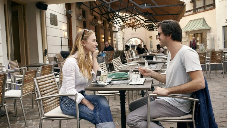 Café Witetschka, © Wiener Alpen/Florian Lierzer Two people are sitting at a table in a street café and talking.
