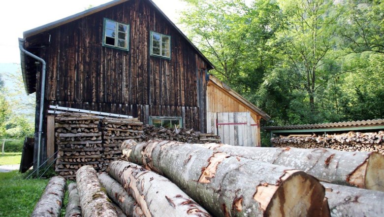 Woodcutter Museum Trübenbach, © weinfranz.at Piles of wood and tree trunks in front of a rustic wooden building outdoors.