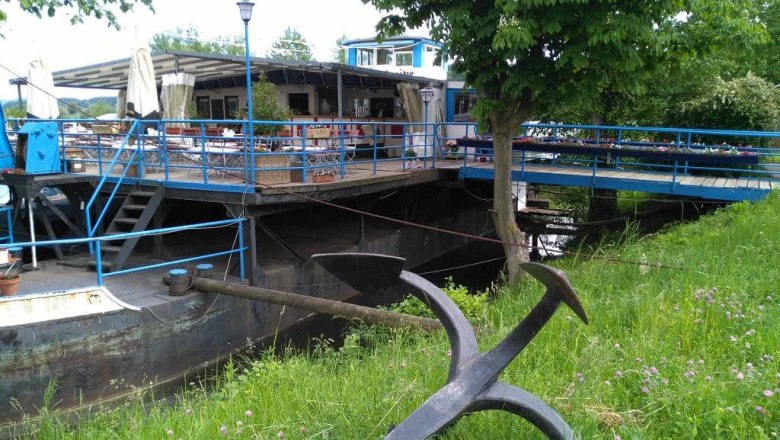 Exterior view of the old ferry, © Restaurant "Alte Fähre" Exterior view of a restaurant on an old ferryboat with blue balustrade and green surroundings.