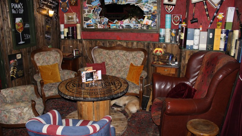 Sitting by the fireplace, © Mary´s Scottish Coffeepub Cozy room with armchairs, table and dog on carpet.