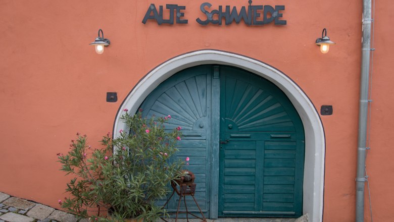The Old Court Gate, © Alte Schmiede Schönberg Old gate with the inscription 'Alte Schmiede' and plants in front of it.