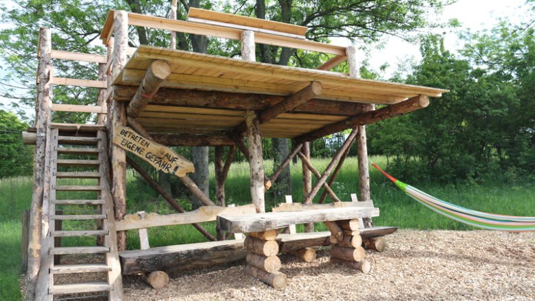 Balcony Tullnerfeld, © Gemeinde Tulbing, Thomas Gattinger Wooden platform with table and hammock outdoors.