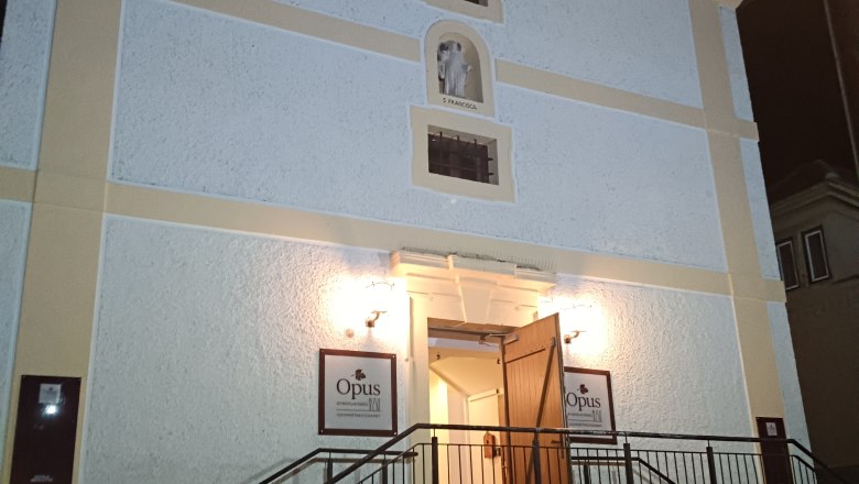 Opus exterior view, © Nicolas Engel Entrance of a building with stairs and open doors, illuminated at night.