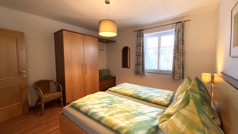 Vacation apartment Traube, © Trachsler Bedroom with double bed, closet, chair and window.