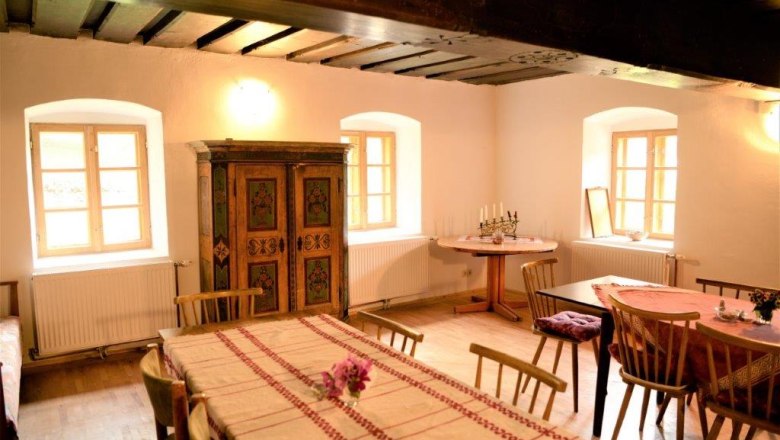 Parlor - Mariahaus, © Martina Heilingsetzer Cozy living room with wooden furniture, tablecloths and a painted cupboard.