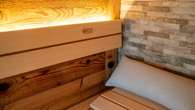 Chalets & places full of WONDER - Weidehaus De Luxe, © WUNDERVOLL eben Interior view of a sauna with wood paneling and stone wall.