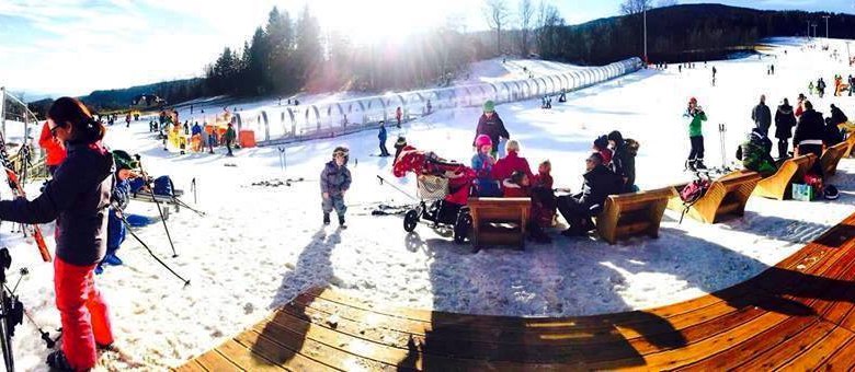 Family ski area, © ©familienarena Winter landscape with people skiing and relaxing on benches in the snow.