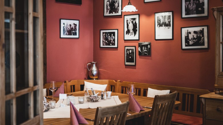Guest room in Rust im Tullnerfeld, © Niederösterreich Werbung/David Schreiber Cozy restaurant with wooden table, red walls and framed photos.