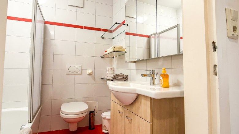 House Morgensonne Bathroom, © Fam. Pauker Modern bathroom with red tiles, white ceramics and mirrors.