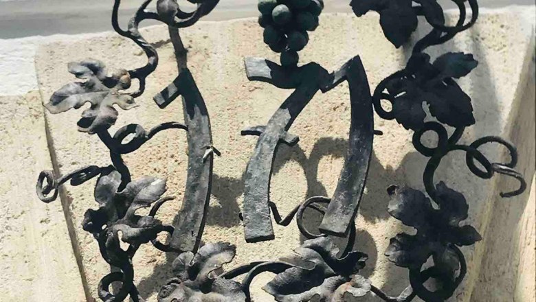 Old handicraft, © Familie Stagard Metal decoration with grape motif and the number 1717 on a stone arch.