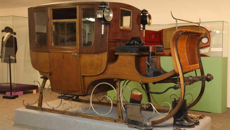 Travel sledges, © Peter Pokorny An antique wooden traveling sledge with lanterns, exhibited in a museum.