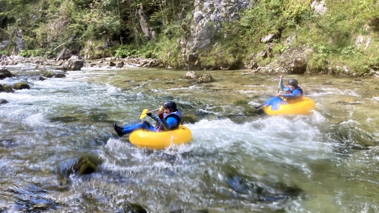 Tubing Wilderness Center Nasswald, © Georg Bergthaler Two people tubing on a river in a wooded area.