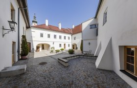 FineArtGallerie Traismauer exterior, © FineArtGallerie Inner courtyard of the TDR-FineArtGallery in Traismauer with cobblestones and white buildings.