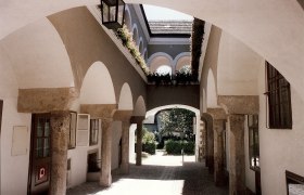 Arcaded courtyard in the Hafnerhaus, © Karanitsch An arcaded courtyard with stone arches and flowers in the Hafnerhaus.