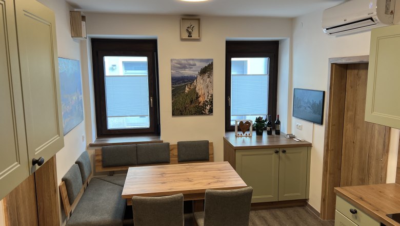 Kitchen vacation home Höflein, © Anton Sommer Modern kitchen with wooden furniture, dining table and green cupboards.