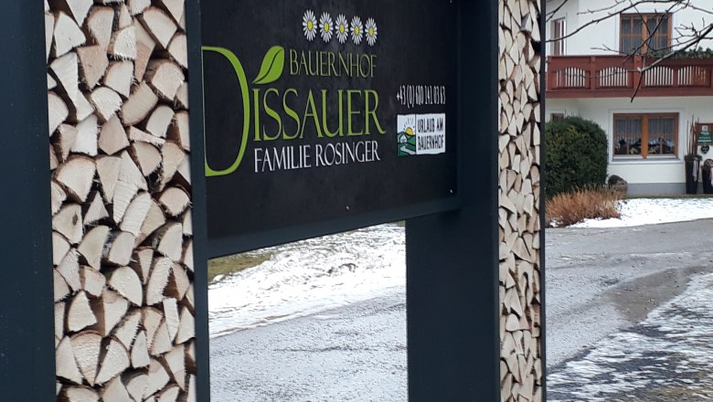 Court board, © rosinger Sign of a farm with piles of wood and a house in the background.