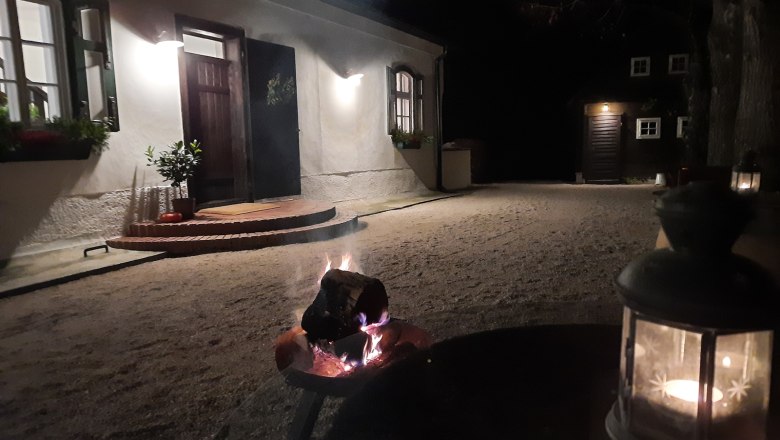 Country estate Oberhof, © Landsitz Oberhof An illuminated courtyard at night with a fire basket and a lantern in the foreground.