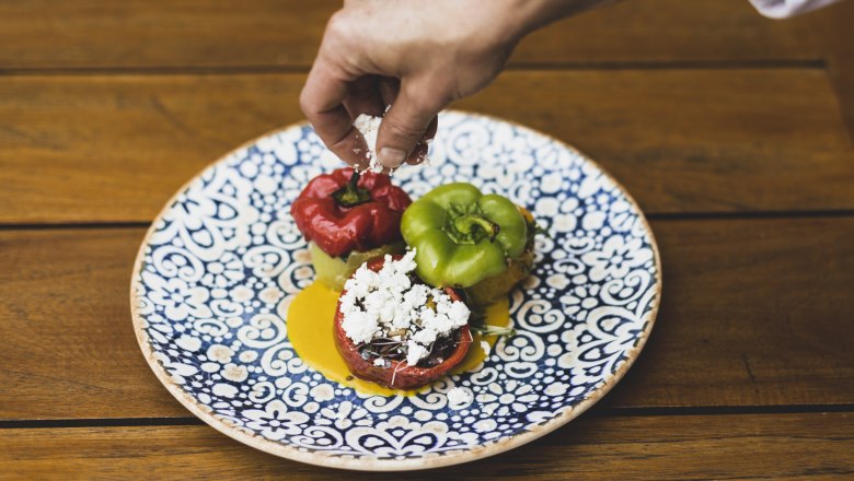Stuffed peppers, © Niederösterreich Werbung/David Schreiber A plate of stuffed peppers, decorated with cheese, on a wooden table.