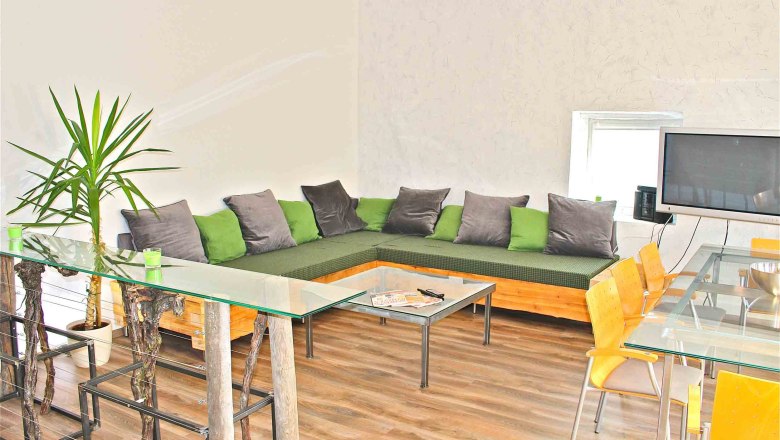 vacation-living, © Frau Lendl Modern living room with corner sofa, glass table and TV.