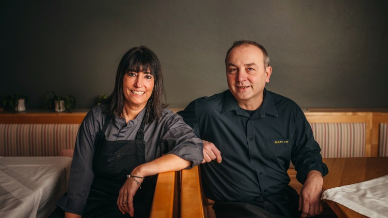 Hosts Barbara and Manuel Langer, © Niederösterreich Werbung/Daniela Führer Two people in work clothes sit smiling in a restaurant.