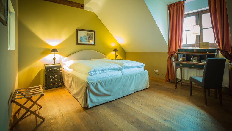 Double room with castle view, © Schlossschenke Cozy double room with wooden floor, double bed, desk and window with curtains.