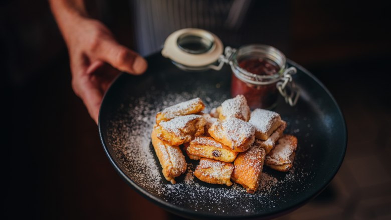 Kaiserschmarren with stewed plums, © Niederösterreich Werbung/Daniela Führer A plate of Kaiserschmarren, dusted with powdered sugar, and a glass of Zwetschkenröster.